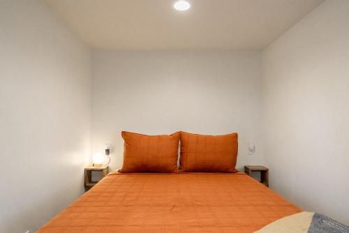 a bed with orange pillows in a white room at Casitas at Capitol Reef in Torrey