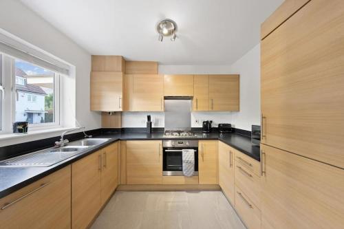 a large kitchen with wooden cabinets and a sink at The Bridge 2 Bedroom House in Dartford