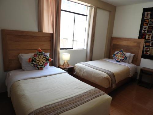 a hotel room with two beds and a window at Ayllu B&B Ollantaytambo in Ollantaytambo