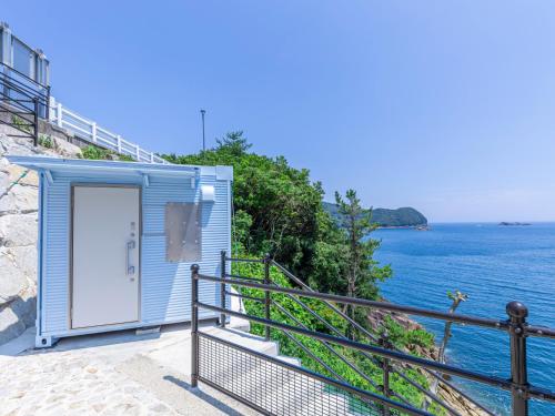 a blue building on the side of the ocean at Hotel Nami in Kumano
