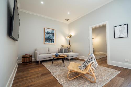a living room with a couch and a table at Belle Escapes - Moseley Apartments near the beach with private garden in Glenelg