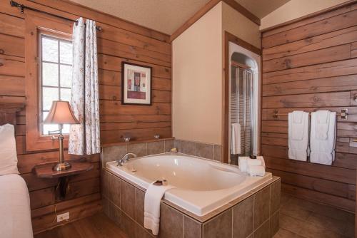 ein Badezimmer mit Badewanne in einem Zimmer mit Holzwänden in der Unterkunft La Bannik in Ville-Marie