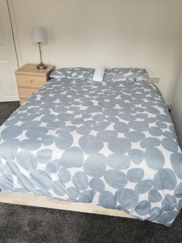a bed with a blue and white comforter on it at Cosy Home Stay in Etruria