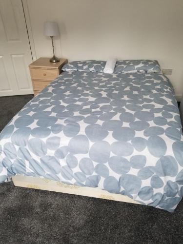 a bed with a blue and white comforter on it at Cosy Home Stay in Etruria