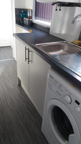 a kitchen with a sink and a washing machine at Cosy Home Stay in Etruria