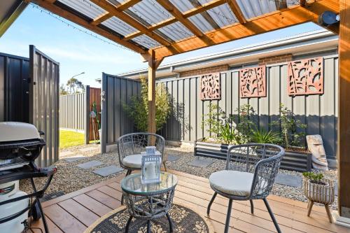 a patio with a table and chairs and a grill at The Bayswood Retreat on Moona Creek by Experience Jervis Bay in Vincentia