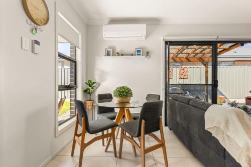 a living room with a table and chairs and a couch at The Bayswood Retreat on Moona Creek by Experience Jervis Bay in Vincentia