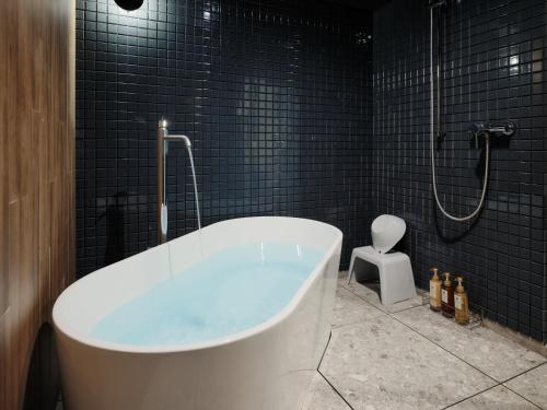 a bath tub in a bathroom with black tiles at MONday Apart Premium Asakusa in Tokyo
