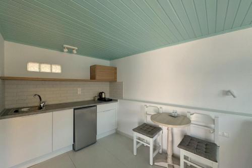 a kitchen with a table and a green ceiling at Eleni On The Beach in Katapola