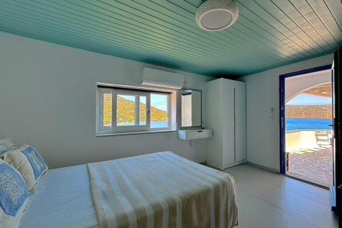 a bedroom with a bed in a room with a window at Eleni On The Beach in Katapola