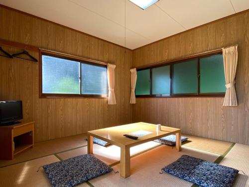 a living room with a table and two windows at Tengu Onsen Asama Sanso in Komoro