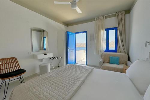 a white bedroom with a bed and a chair at Eleni On The Beach in Katapola