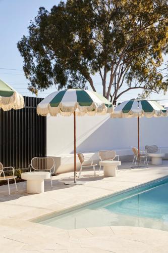 a swimming pool with chairs and umbrellas next to a pool at The Clairfield Hotel in Mudgee