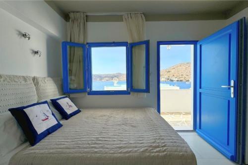 a bedroom with a large bed with blue windows at Eleni On The Beach in Katapola