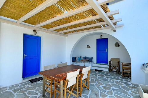 a dining room with blue doors and a table at Eleni On The Beach in Katapola