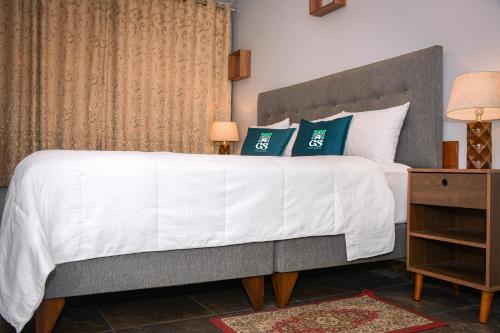 a bedroom with a large white bed with green pillows at GS Hoteles- Callao in Lima