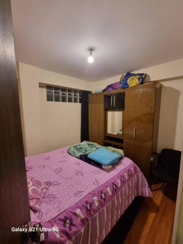 a small bedroom with a bed with a purple blanket at Oruro tierra de amor y de carnaval in Oruro