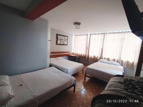 a hotel room with three beds and a window at GS Hoteles- Callao in Lima
