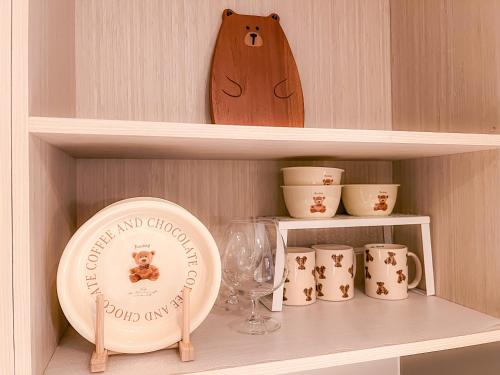 a shelf with a plate and cups and a wine glass at Gold Coast PIK Apartments by Host Jess in Jakarta