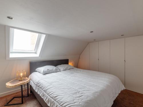 Un dormitorio con una gran cama blanca con ventana. en Renovated Flat near Beach, en De Haan
