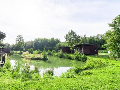 a river in a grassy field with two buildings at Nature Retreat in Antoing in Antoing