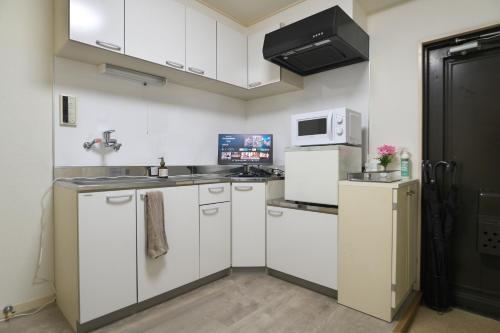 東京にあるZen Abode404 Japanese-style and modern Western-style roomsの白いキャビネットと電子レンジを備えたキッチン