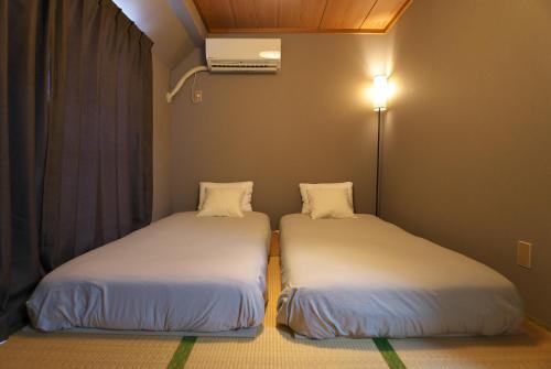 two beds in a room with a light on the wall at Zen Abode404 Japanese-style and modern Western-style rooms in Tokyo