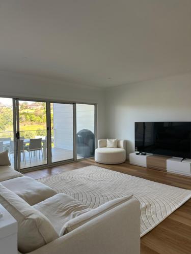 a living room with a large television and a couch at Surfleet Retreat Kiama in Kiama