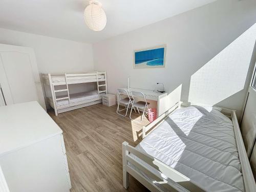 une petite chambre avec un lit et un bureau dans l'établissement Appartement rénové avec tennis privé, parking et vue mer - FR-1-361-162, à Jullouville