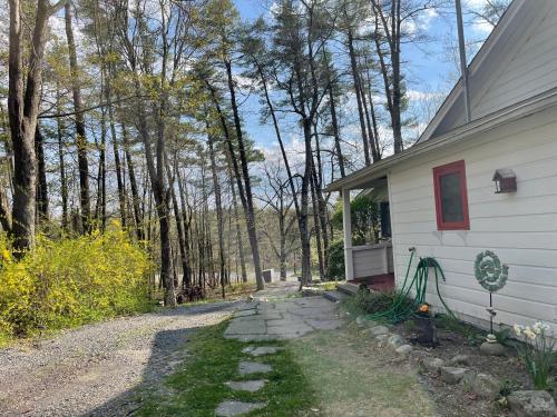 a driveway next to a white house with trees at Enchanted Woodstock Cottage with hot tub in West Hurley