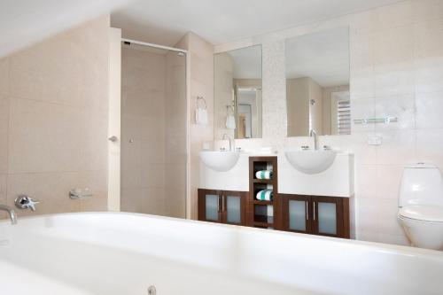 a bathroom with two sinks and a tub and a toilet at Mantra on Salt Beach in Kingscliff
