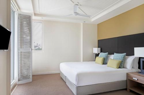 a white bedroom with a large bed and a television at Mantra on Salt Beach in Kingscliff