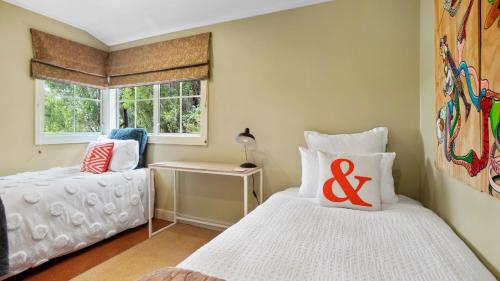 a bedroom with two beds and a window at A Ray of Sunshine - Manly Holiday Home in Whangaparaoa