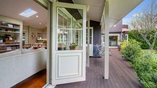a pivot door in a house with a porch at A Ray of Sunshine - Manly Holiday Home in Whangaparaoa