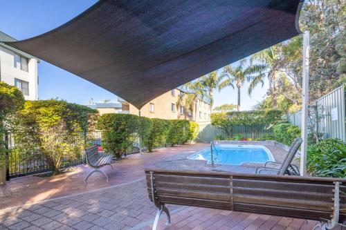 a patio with a bench and a swimming pool at The Point 13, 5-7 Mitchell St - stunning water views, complex pool and WiFi in Soldiers Point
