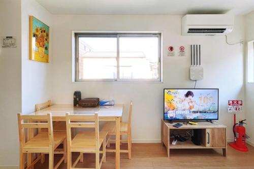 a dining room with a table and a tv at SKYE HOMEⅡ本羽田 in Tokyo