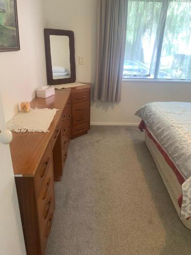 a bedroom with a bed and a dresser and a mirror at Hosts on the Coast Happy Day's on the 7th in Pauanui