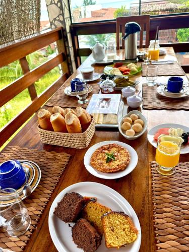 einen Holztisch mit Teller mit Essen und Brot in der Unterkunft Pousada Bella Mar in Prea