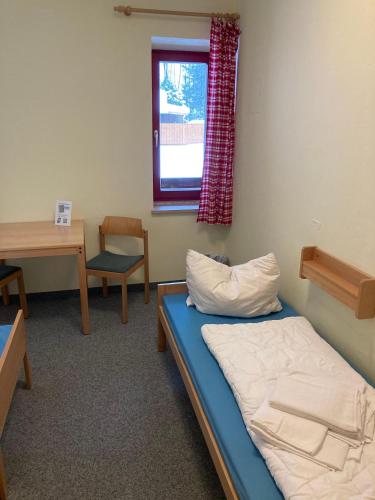 a room with a bed and a desk and a window at ALPEN EXPERIENCE - CVJM Aktivzentrum Hintersee, Jugendgästehaus in Ramsau