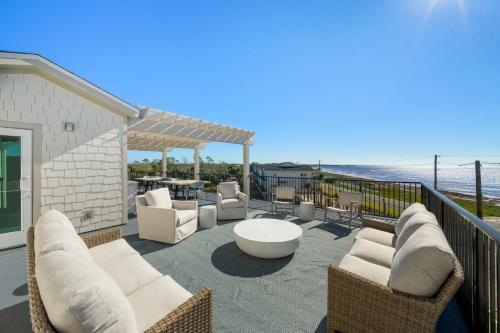 a patio with white chairs and tables and the ocean at Salty Breeze by Pristine Property Vacation Rentals in Saint Joe Beach