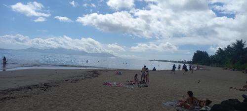 a group of people on a beach near the water at Kimmy Tahiti House in Punaauia