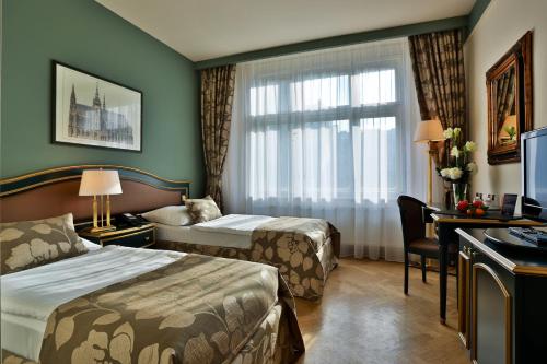 a hotel room with two beds and a desk and a window at Elysee Hotel in Prague
