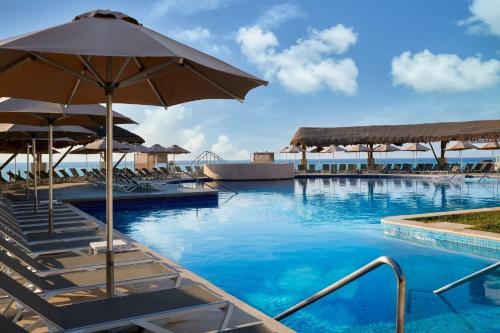 a swimming pool with chairs and an umbrella at Marriott Cancun, An All-Inclusive Resort in Cancún