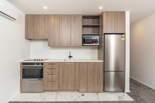 a kitchen with wooden cabinets and a stainless steel refrigerator at Central Apartment Stone Throw from Hospital in Addington