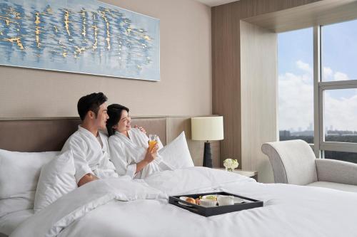 a man and woman sitting in bed in a hotel room at Nanning Marriott Hotel in Nanning