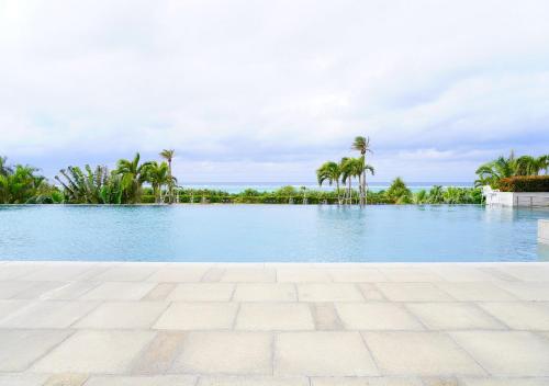 a large swimming pool with palm trees in the background at Hotel Monterey Okinawa Spa & Resort in Onna