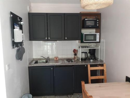 - une cuisine avec des placards noirs et un évier dans l'établissement Appartement confortable 2 pièces avec balcon, proche télécabine et commerces à Valfréjus - FR-1-561-114, à Modane