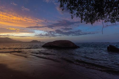 a beach with a large rock in the water at Arrecifes Refugio Natural in Santa Marta