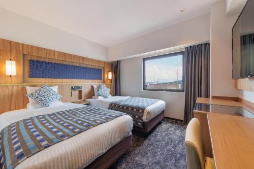 a hotel room with two beds and a television at Art Hotel Morioka in Morioka