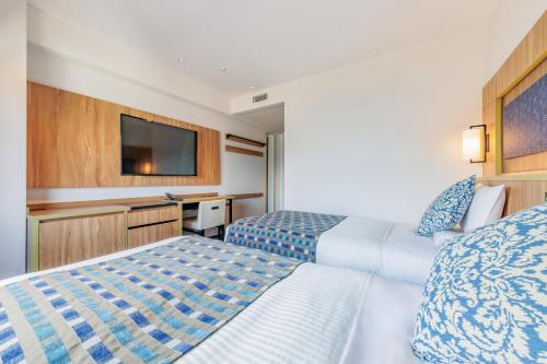 a hotel room with two beds and a flat screen tv at Art Hotel Morioka in Morioka
